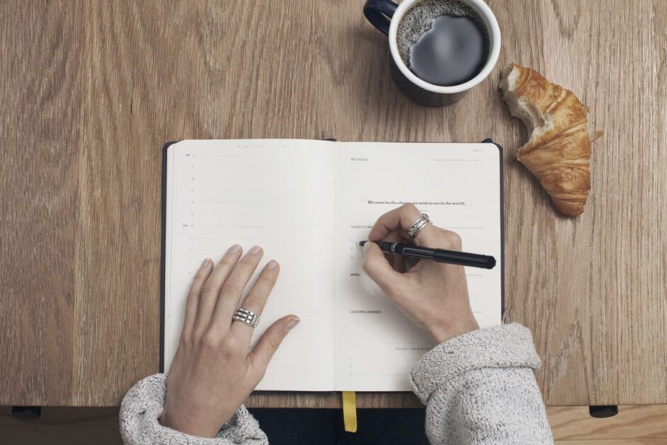 Dance school timetable: planning your September classes Hands writing in a planner beside a cup of coffee while planning a dance school timetable